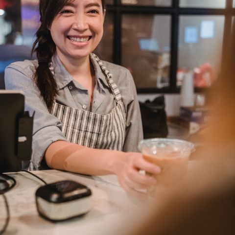 Nora, smiling behind the counter