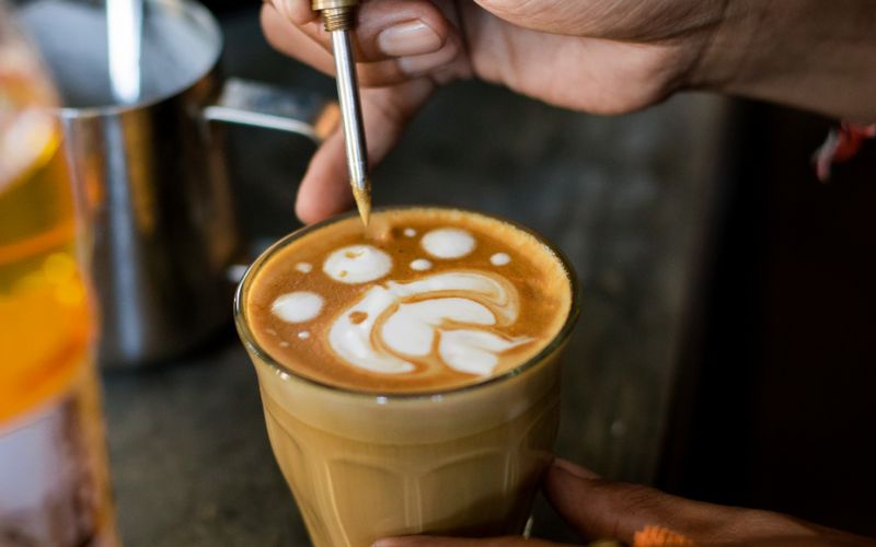 Hands pouring a rosetta into a cup of coffee