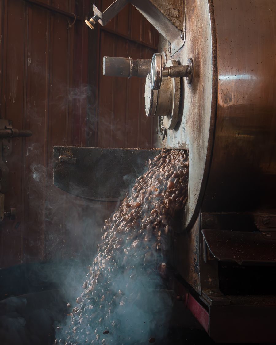 Freshly roasted beans pouring out of the roaster in a cloud of steam
