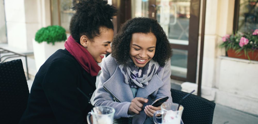 Two friends laughing over coffee at a table