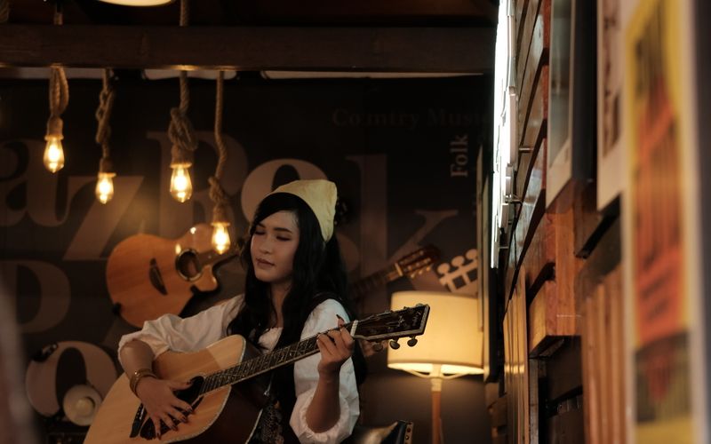 A woman playing acoustic guitar in a small café